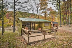 eine grüne Hütte mit einer Terrasse im Wald in der Unterkunft Lone Ranger Cabin with 50 Acres by Raystown Lake in Huntingdon
