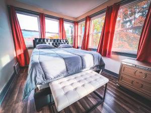 a bedroom with a bed and windows with red curtains at The Trotter Manor- With Private Yard & Free Parking, Minutes From Falls & Casino by Niagara Hospital in Niagara Falls