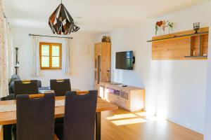 a dining room with a table and chairs and a television at Ferienwohnungen Heillinger Gütl in Ruhpolding