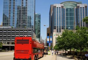 a red double decker bus driving down a city street at Embassy Suites by Hilton Chicago Downtown Magnificent Mile in Chicago