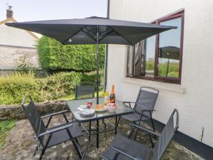 a table and chairs under a black umbrella at Moorstone in Okehampton