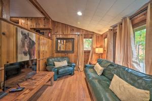 a living room with a green couch and a television at Wyatt Earp Cabin with Deck, 1 Mi to Raystown Lake! in Huntingdon