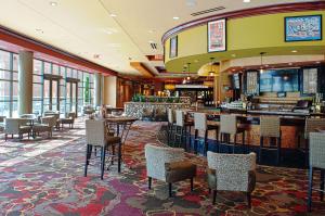 a restaurant with tables and chairs and a bar at Embassy Suites by Hilton Charlotte Concord Golf Resort & Spa in Concord