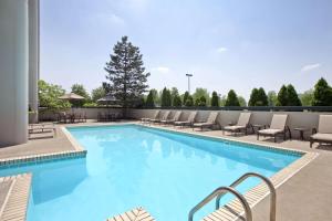 una gran piscina con tumbonas y mesas. en Embassy Suites by Hilton Columbus, en Columbus
