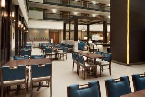 a dining room with tables and chairs and a bar at Embassy Suites by Hilton Columbus in Columbus