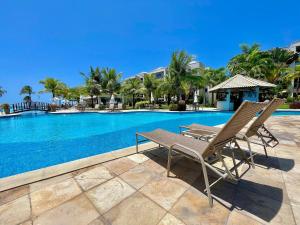 a pair of chairs sitting next to a swimming pool at Wai Wai Cumbuco Resort in Cumbuco