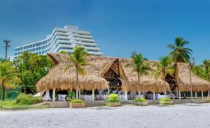 un complejo con palmeras y techo de paja en Hilton Cartagena en Cartagena de Indias