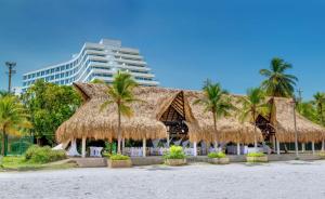 un complejo con palmeras y techo de paja en Hilton Cartagena, en Cartagena de Indias