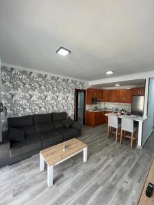 a living room with a black couch and a table at Acogedor apartamento con piscina yedae in Gáldar