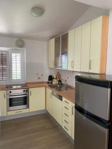 eine Küche mit weißen Schränken und einem Kühlschrank aus Edelstahl in der Unterkunft Sunset Villa Brela in Brela
