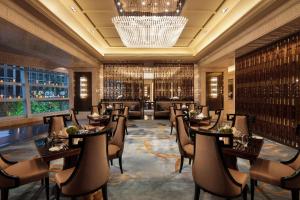 a restaurant with tables and chairs and a chandelier at Conrad Dalian in Dalian