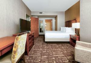 a hotel room with a bed and a flat screen tv at Embassy Suites by Hilton Dallas Frisco Hotel & Convention Center in Frisco