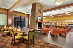 a restaurant with tables and chairs and a fireplace at Hampton Inn & Suites Dallas-Mesquite in Mesquite