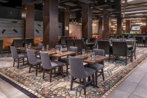 a restaurant with wooden tables and chairs on a rug at DoubleTree by Hilton Hotel Denver - Aurora in Aurora