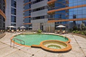 DoubleTree by Hilton Hotel and Residences Dubai – Al Barsha في دبي: مسبح امام مبنى طويل