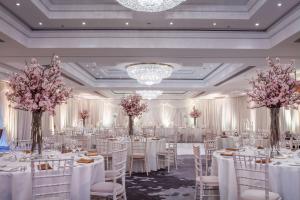 un salón de banquetes con mesas y sillas blancas y flores rosas en Conrad Dublin en Dublín