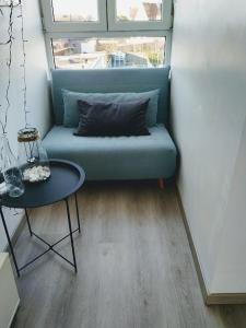 a blue couch sitting in a room with a table at Greenfee vakantieappartement in De Haan