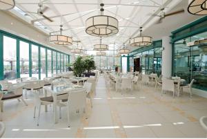 a restaurant with white tables and chairs and windows at Hilton Dubai The Walk in Dubai