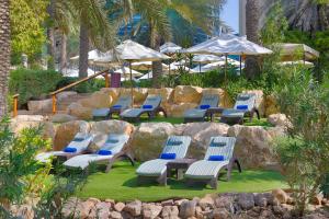 een groep stoelen en parasols in een tuin bij Hilton Dubai Jumeirah in Dubai