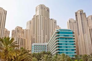 eine Skyline der Stadt mit hohen Gebäuden und Palmen in der Unterkunft Hilton Dubai Jumeirah in Dubai