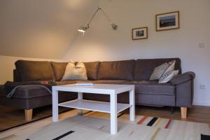 a living room with a brown couch and a white table at Lindenhuus in Fleckeby