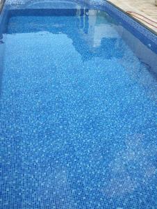 a large blue swimming pool with a reflection in the water at Pousada Acolhedora in Ribeirão Preto