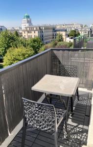 een tafel en stoelen op een balkon met uitzicht op de stad bij Cosy apartment Disneyland Paris en face de la gare RER val d'Europe in Serris