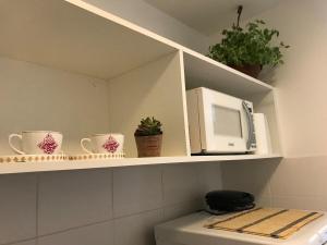 a microwave sitting on a shelf above a toilet at V320 Espaço Inteiro Wi-Fi Exclusivo Área Central in Brasilia