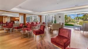 a waiting room with red chairs and tables and windows at Conrad Algarve in Quinta do Lago