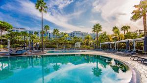 a pool at a resort with chairs and palm trees at Conrad Algarve in Quinta do Lago