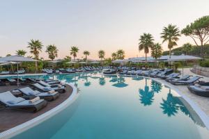 a large swimming pool with lounge chairs and palm trees at Conrad Algarve in Quinta do Lago