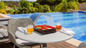 a table with a tray of food and two glasses of beer at Conrad Algarve in Quinta do Lago