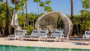 a group of chaise lounge chairs next to a pool at Conrad Algarve in Quinta do Lago