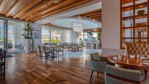 a restaurant with wooden ceilings and tables and chairs at Conrad Algarve in Quinta do Lago