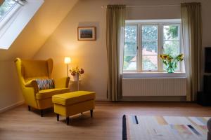 a living room with a yellow chair and a window at Lindenhuus in Fleckeby