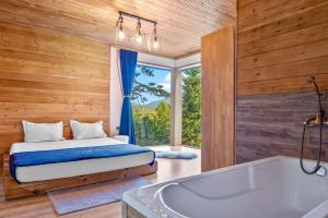 1 dormitorio con cama, bañera y ventana en Forest Lux Boutique Villas, en Rakitovo