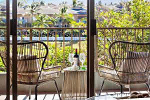 two chairs and a table with a bottle of wine on a balcony at Kahana Manor 619 in Kahana