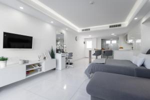 Habitación blanca con 2 camas y TV. en Holiday Home Luxury Loft GC, en Maspalomas