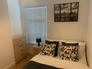 a bedroom with a bed with pillows and a window at Central Stratford Cozy Double Room in London