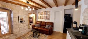 a living room with a leather couch and a stone wall at Magical Oasis for two in Korcula Old Town in Korčula