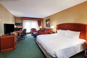 a hotel room with a bed and a flat screen tv at Embassy Suites by Hilton Greensboro Airport in Greensboro