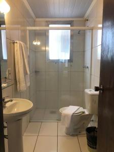 uma casa de banho com um chuveiro, um WC e um lavatório. em Hotel Estoril em Pelotas