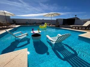 a swimming pool with chairs and a table and an umbrella at Casa Noa in Tuineje