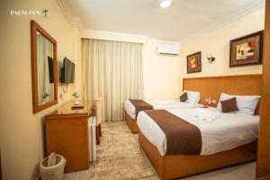 a hotel room with two beds and a television at Palm Inn Suites Hotel in Hurghada