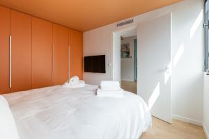 Schlafzimmer mit einem weißen Bett und orangefarbenen Schränken in der Unterkunft Rome Batignolles - Luxe Charme - 2P in Paris
