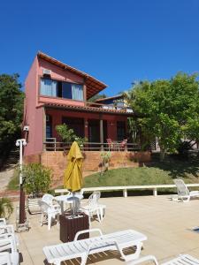 eine Terrasse mit weißen Stühlen und Tischen sowie ein Haus in der Unterkunft Casa de 3 quartos em condomínio em Geriba in Búzios