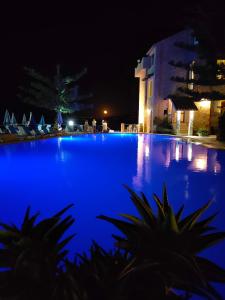 niebieski basen w nocy z budynkiem w obiekcie Hotel La Playa Blanca w mieście Santo Stefano di Camastra