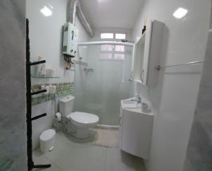 y baño blanco con aseo y ducha. en Loft aconchegante no Leblon, en Río de Janeiro