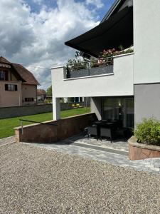 a white house with a balcony with flowers on it at Logement "Le Vôl des cigognes" in Baldenheim