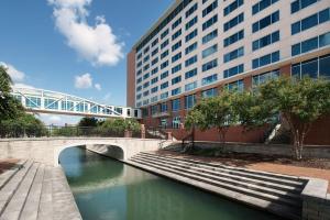 un puente sobre un río frente a un edificio en Embassy Suites Huntsville en Huntsville